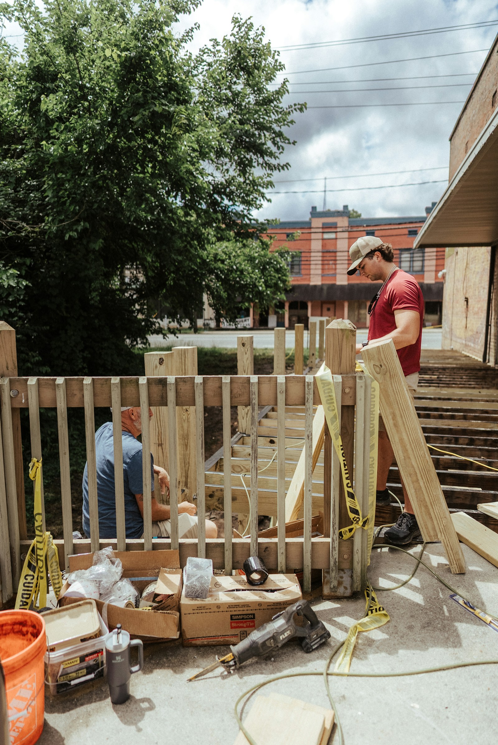 Two workers installing a wood privacy fence on a residential job site